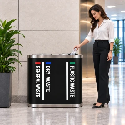 Woman disposing of a plastic bottle into a black SS 202 duo dustbin through its stainless steel swing lid
